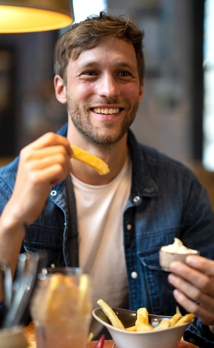 Junger Mann isst Pommes