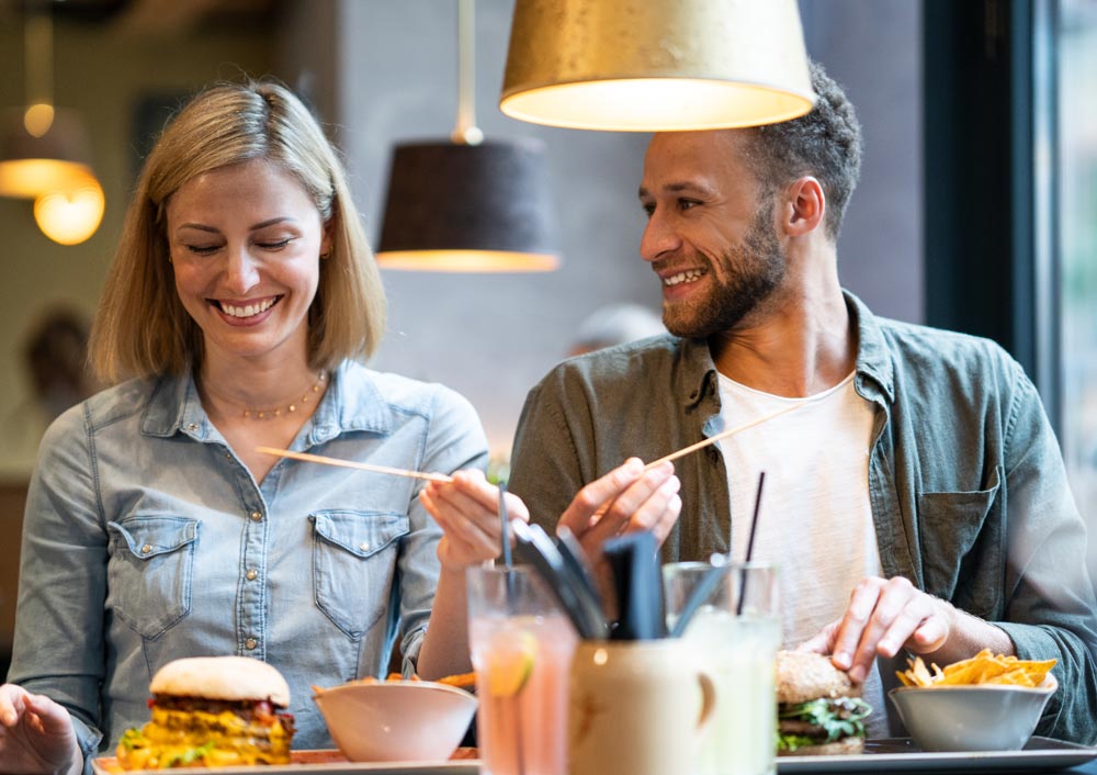 Lächelndes Paar sitzt mit bestelltem Menü am Tisch